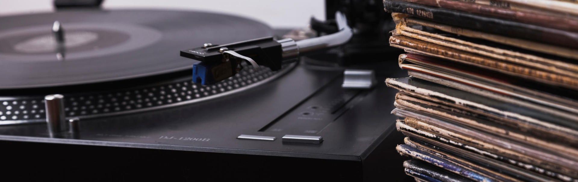 imagem de discos de vinil ao lado de uma vitrola, os discos de vinil estão com suas capas mostrando a importância da proteção para sua conservação