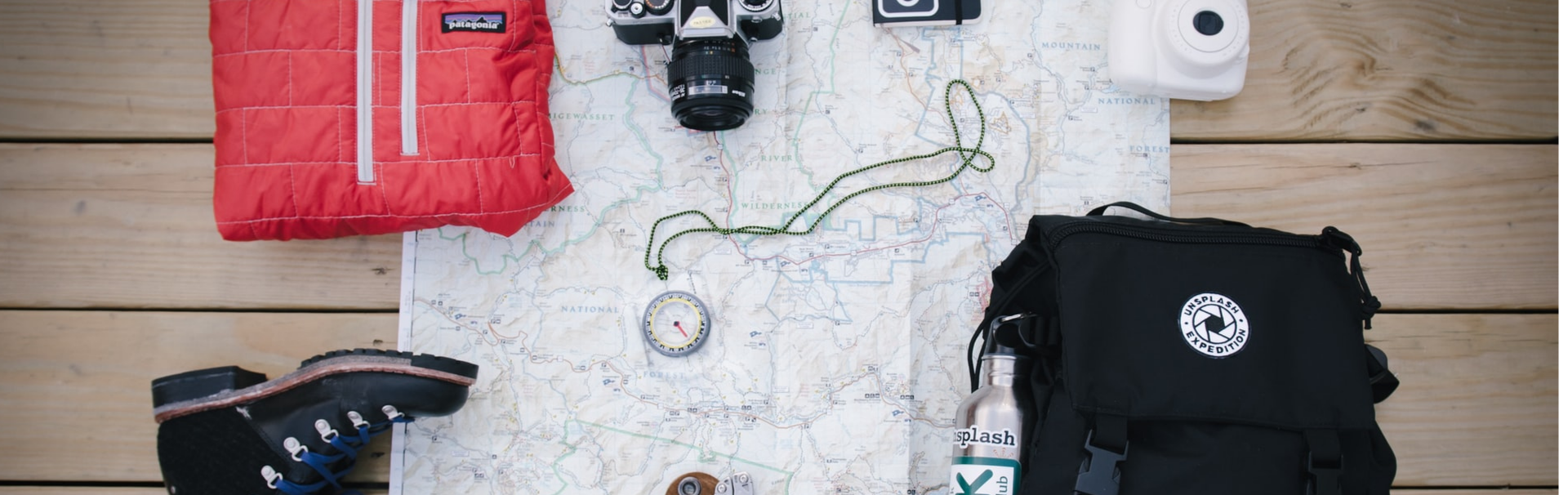 Texto mostrar um mapa e equipamentos para acampar (mochila, botas, bussolas, etc.)